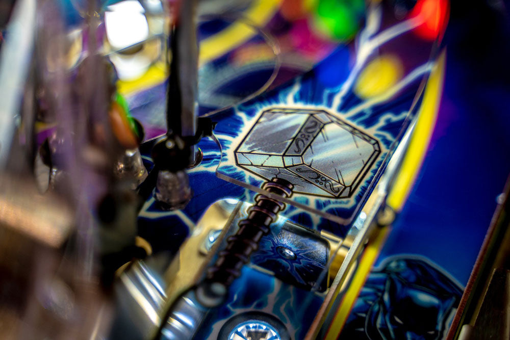 Close-up of a colorful pinball machine with a key-like object on a blue background
