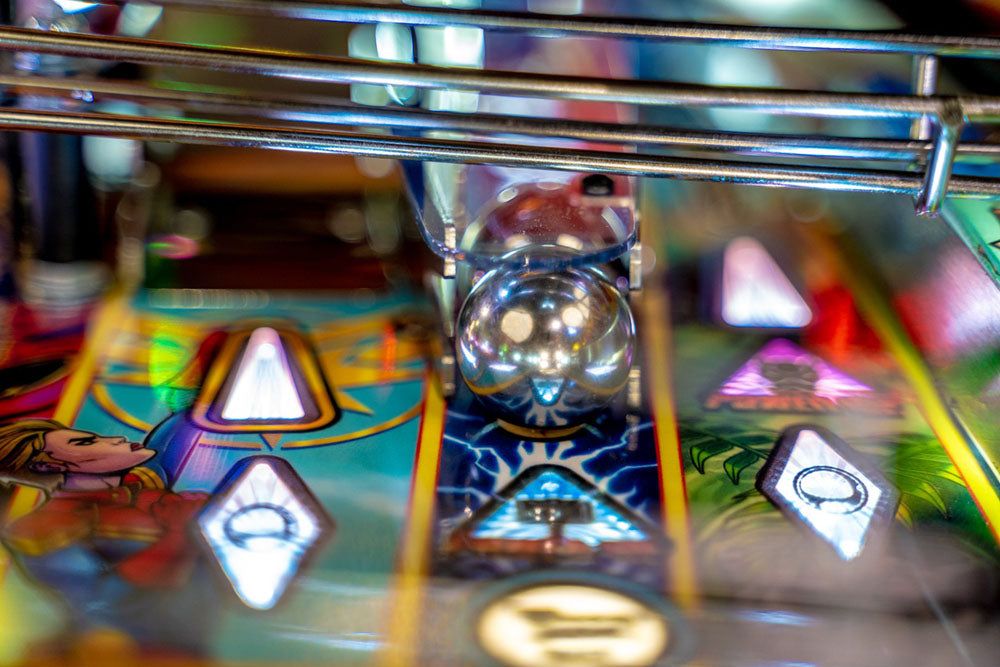 Close-up of a pinball machine with colorful design and metallic elements.