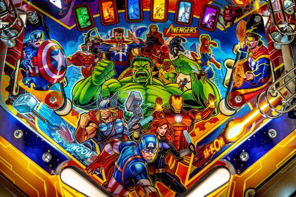 Pinball machine with colorful artwork of superhero characters, including Captain America and Iron Man.