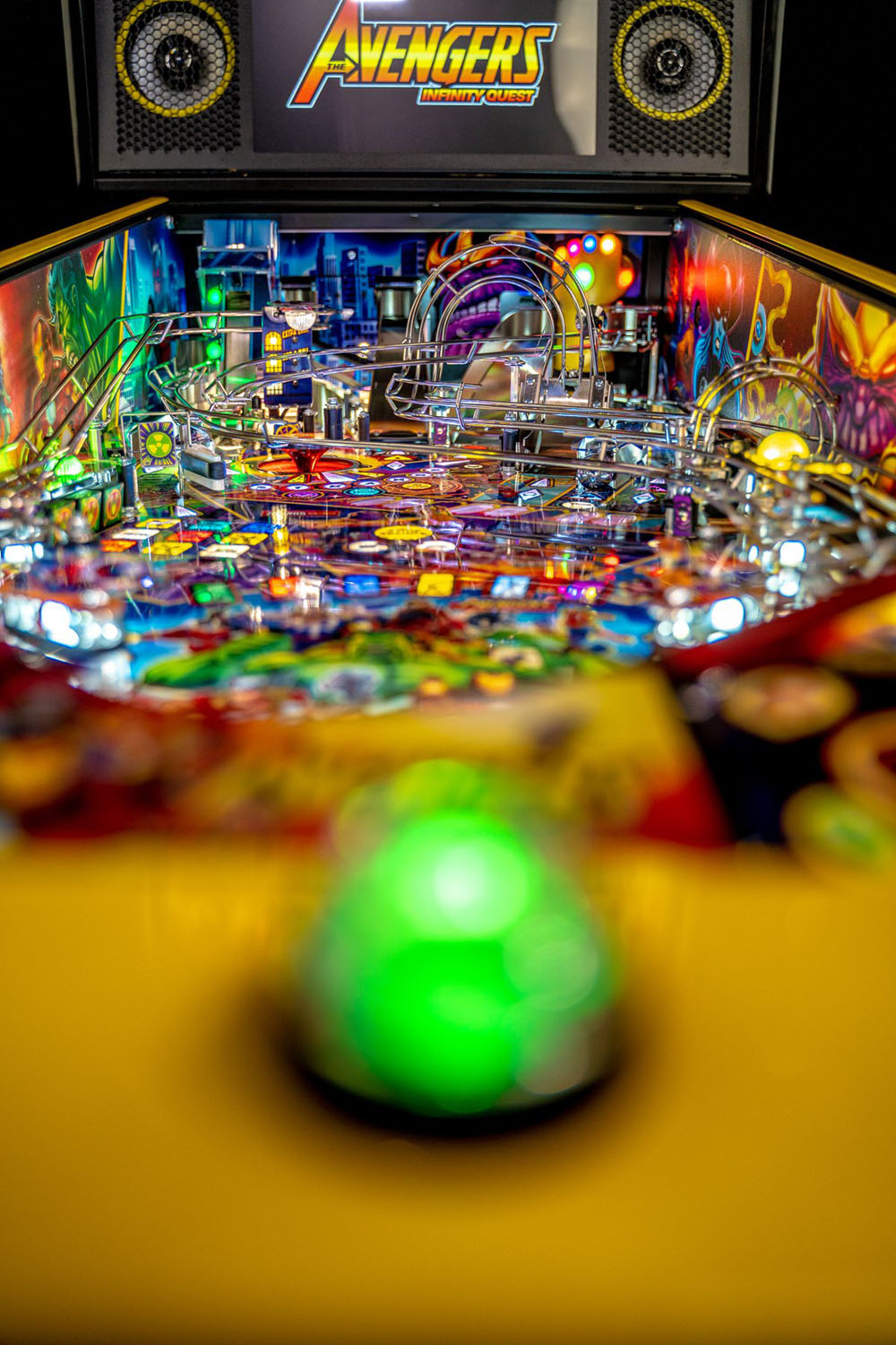 Pinball machine with a green ball in play, featuring the Avengers logo on the screen.