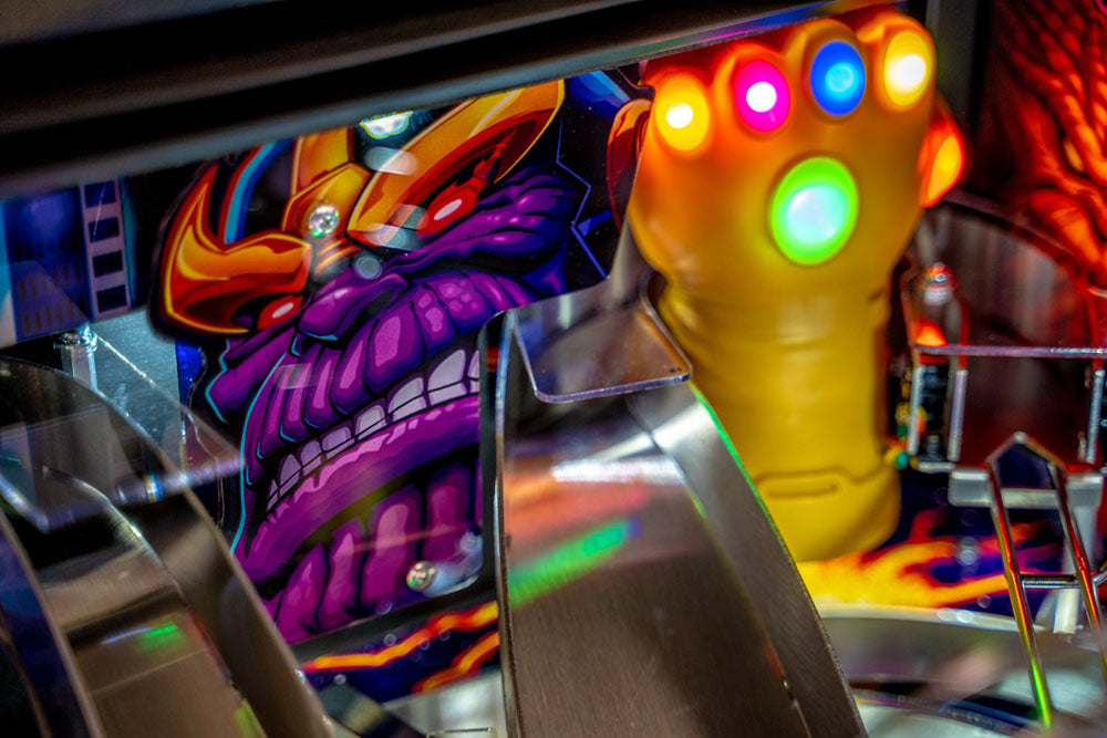 Close-up of a colorful pinball machine with a character and glowing hand