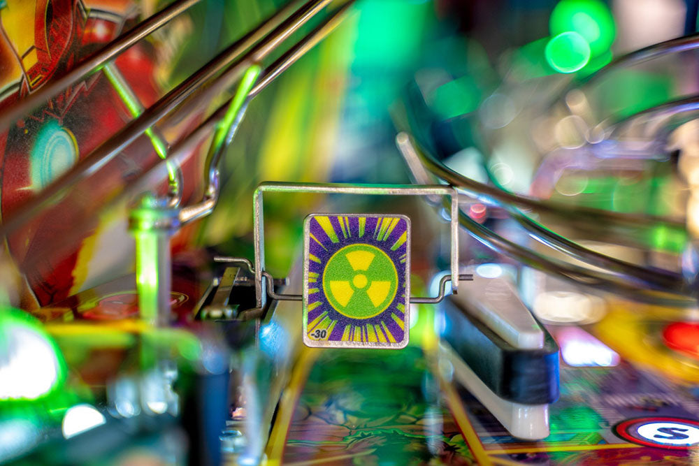 Close-up of a pinball machine with a colorful flipper and a radioactive symbol on the ball.