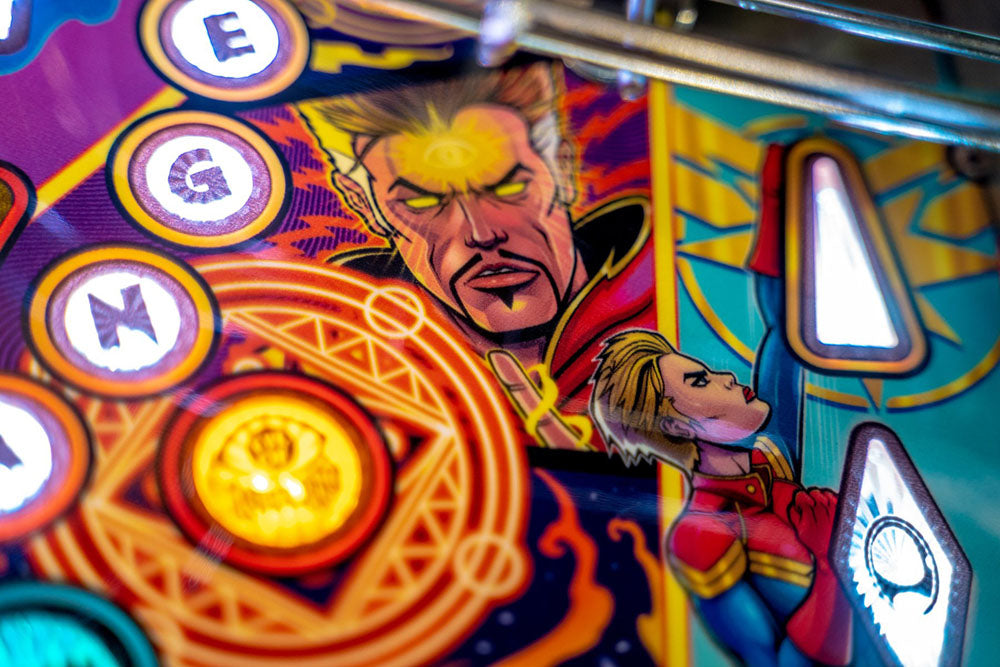 Close-up of a colorful pinball machine with superhero graphics and vibrant colors.