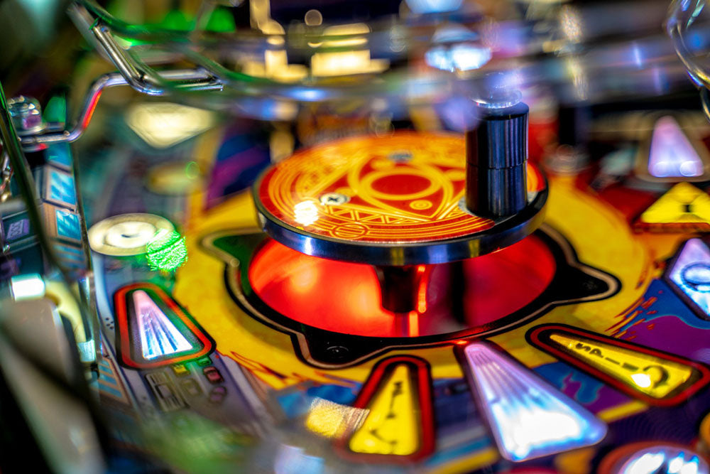 Close-up of a colorful pinball machine playfield with various lights and symbols.