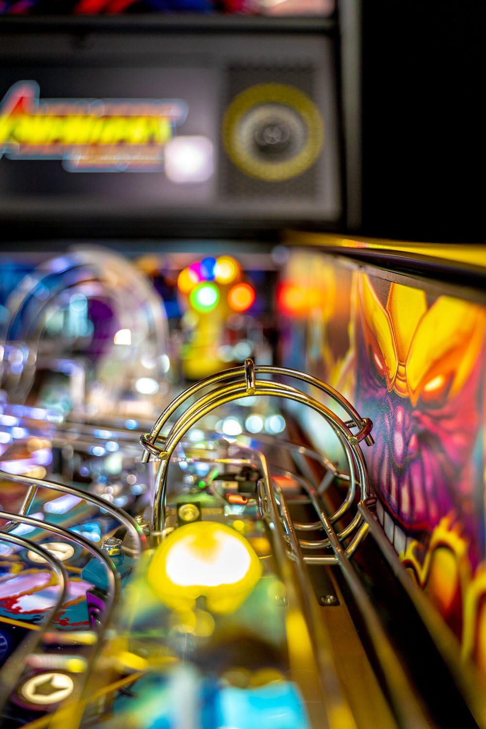 Close-up of a pinball machine with colorful lights and details.