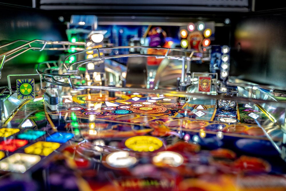 Close-up of a pinball machine with colorful lights and details.
