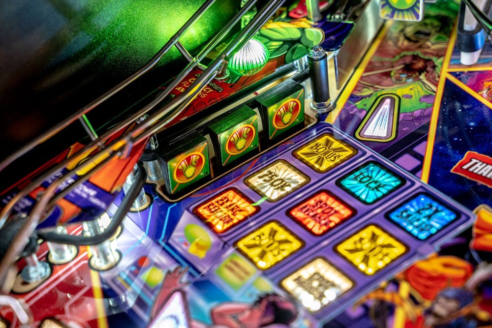 Close-up of a colorful pinball machine with various lights and symbols.