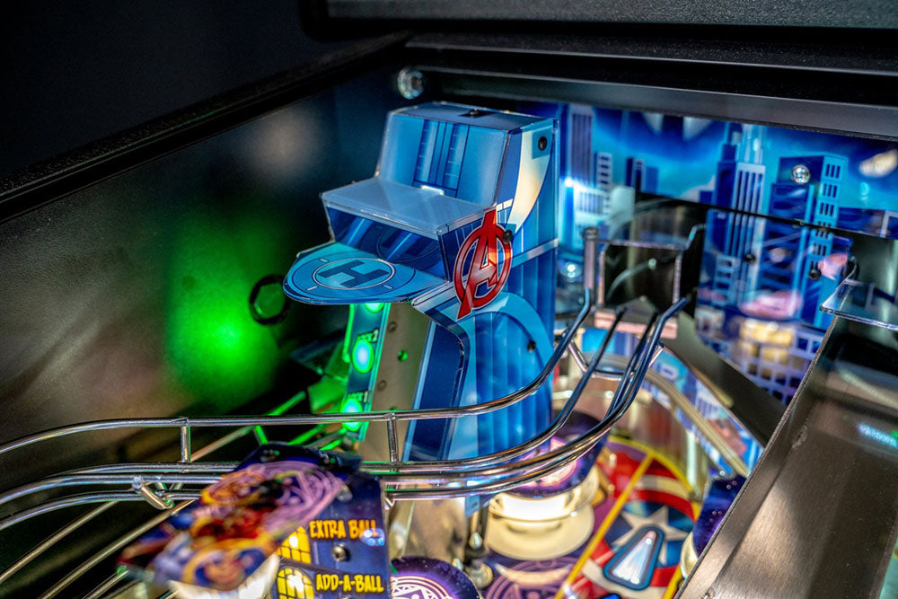 Close-up of a pinball machine with a blue player figure and colorful marbles.