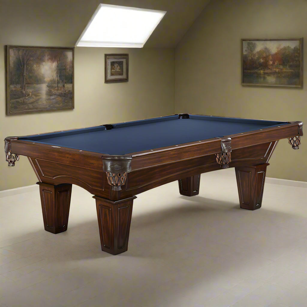 Wooden pool table with blue felt in a room with light-colored walls and ceiling lights.