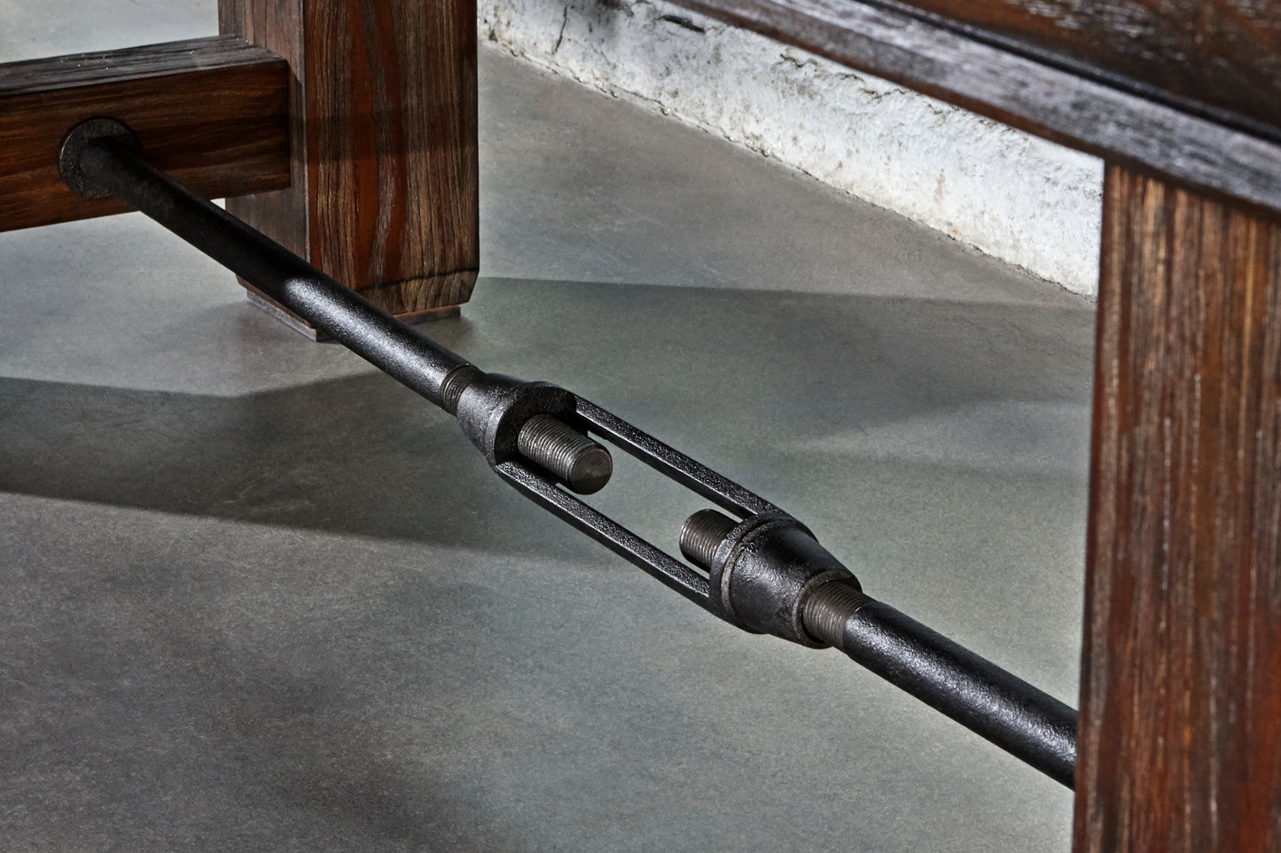 Metallic rod with a wooden shuffleboard table in the background.