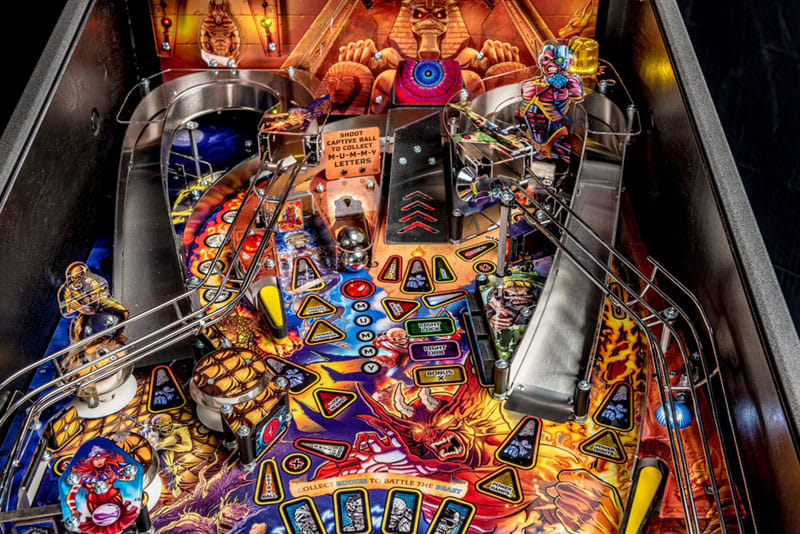 Colorful pinball machine with various symbols and players in an indoor setting