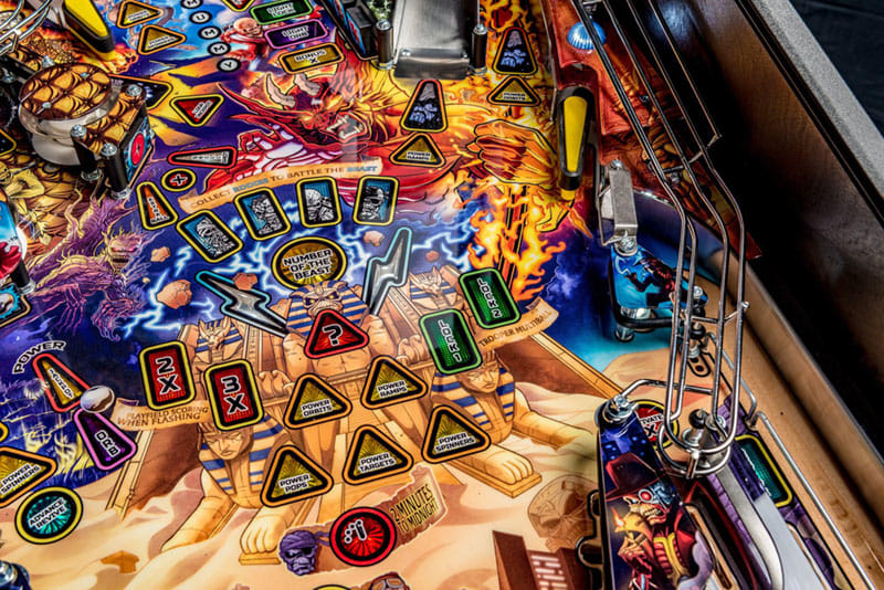 Close-up of a colorful pinball machine with various symbols and lights.