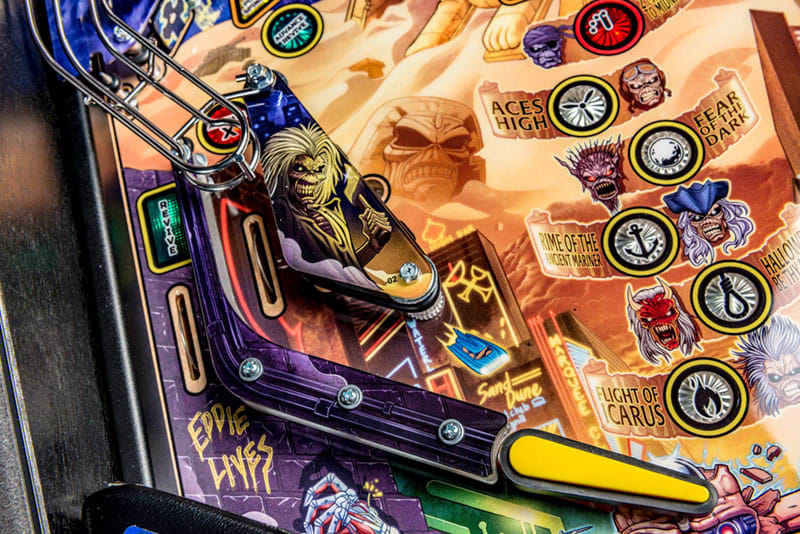 Close-up of a pinball machine with colorful artwork and player's shoe on the playfield.