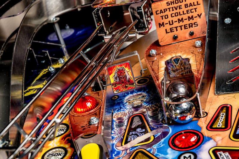 Close-up of a pinball machine with colorful artwork and mechanical components.