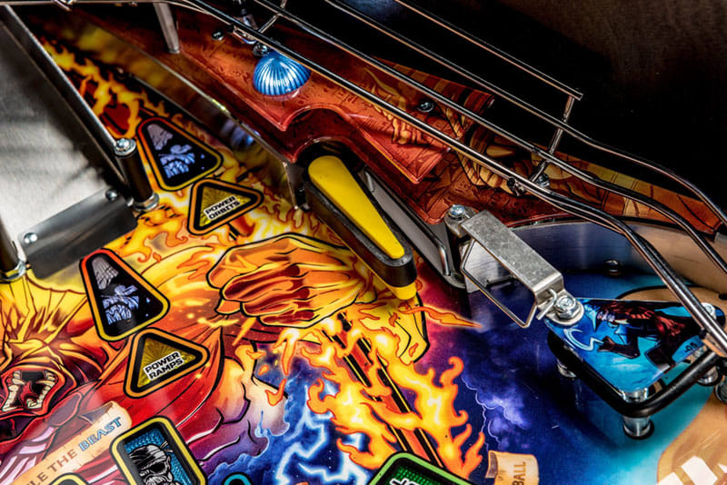 Close-up of a pinball machine with colorful design and mechanical components.