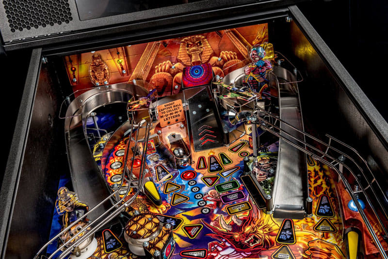 Close-up of a colorful pinball machine with various symbols and lights.