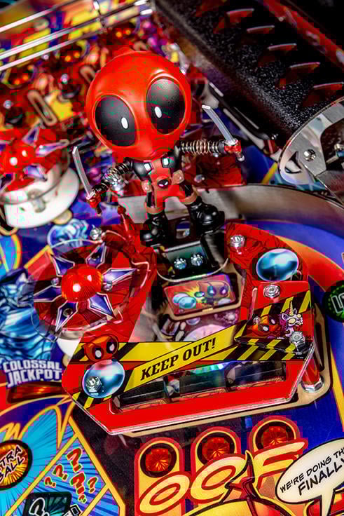Pinball machine with a Deadpool figure and colorful playfield
