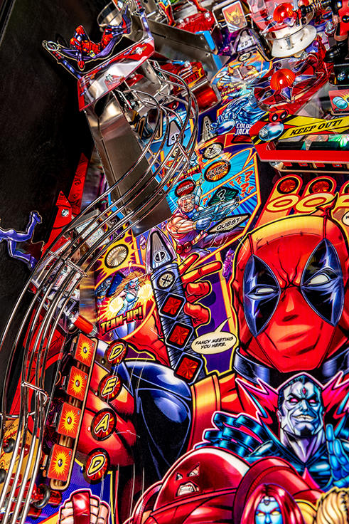 Pinball machine with Deadpool character details. 