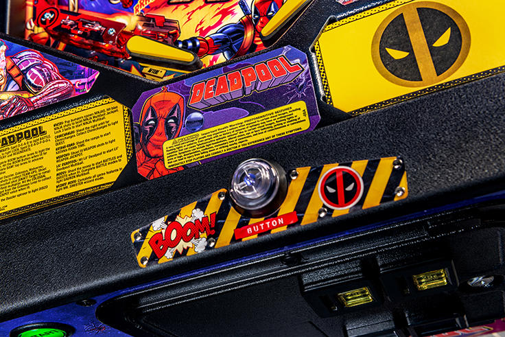 Close-up of a Deadpool-themed pinball machine with colorful graphics and text.