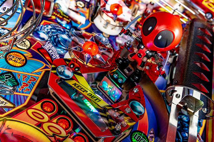 Close-up of a pinball machine with a Deadpool figure and colorful playfield