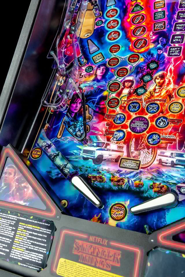 Pinball machine with 'Stranger Things' theme featuring characters and Netflix branding.