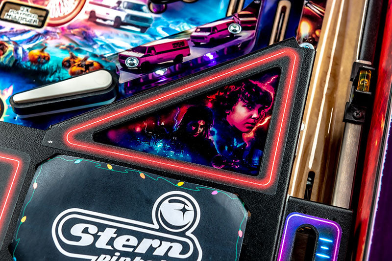 Close-up of a Stern pinball machine with colorful lights and a player's face on the screen.