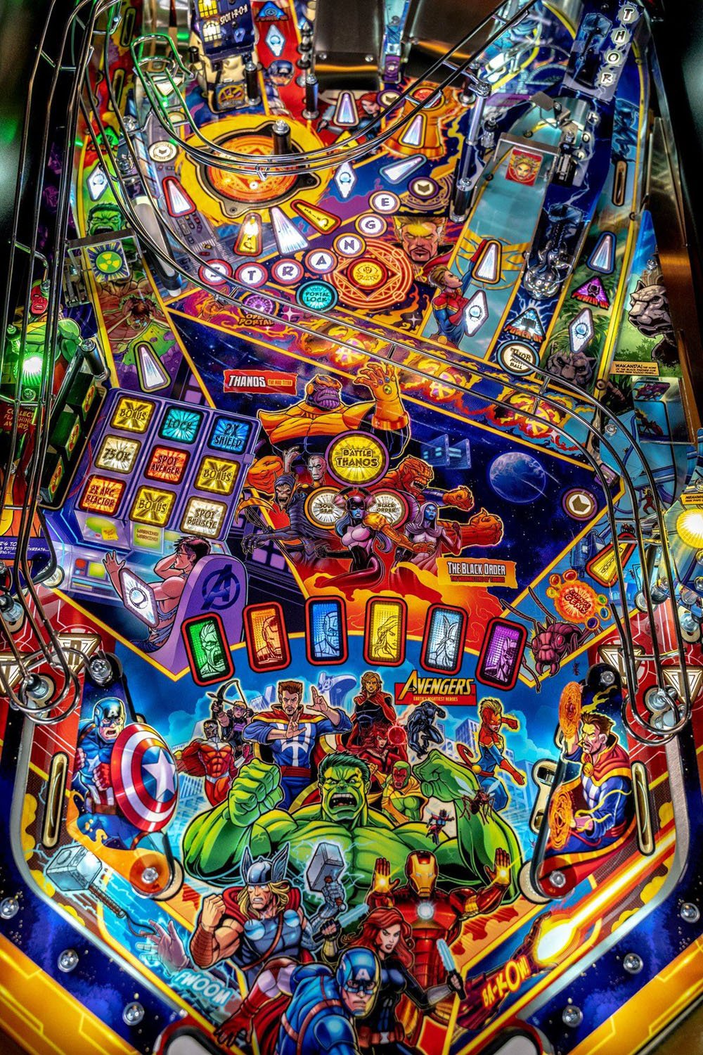 Colorful pinball machine with superhero characters on a dark background