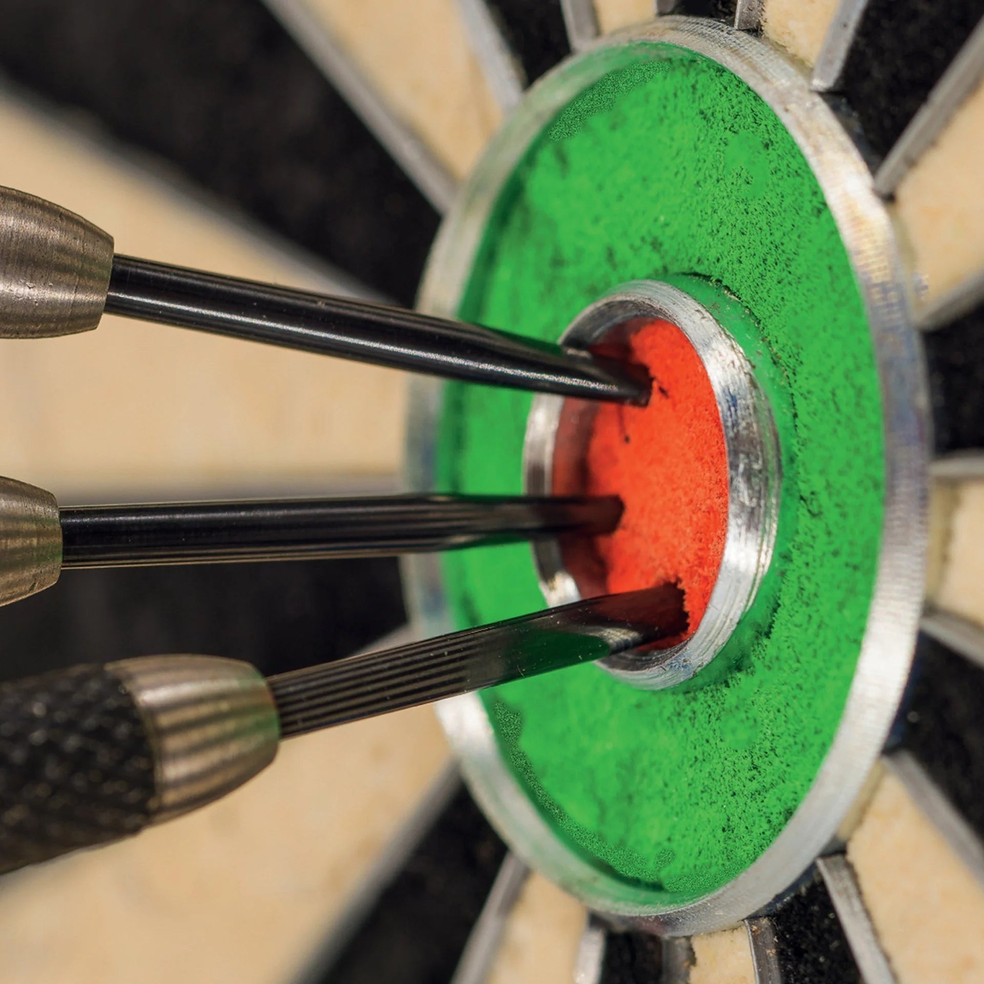 Three darts embedded in a dartboard with green and red sections.