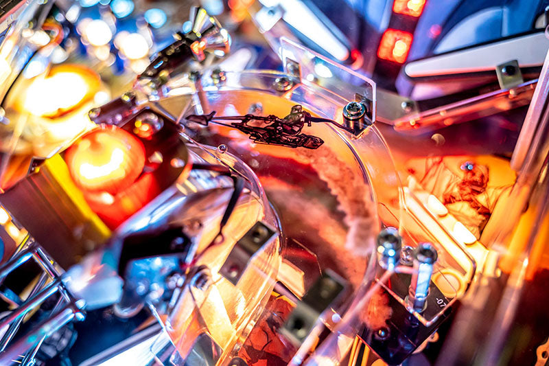 Close-up of a pinball machine with colorful lights and mechanical components.