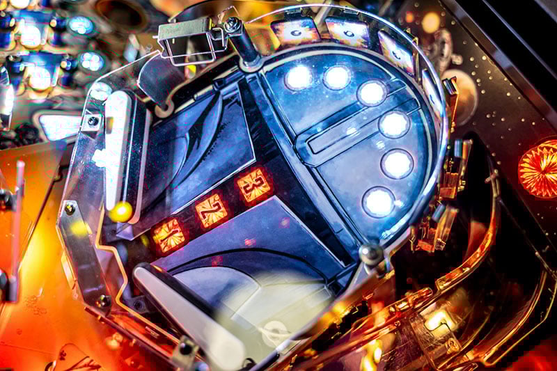 Close-up of a pinball machine with bright lights and reflective surfaces