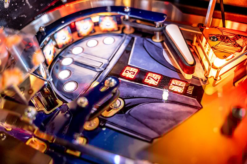Close-up of a pinball machine with glowing lights and buttons