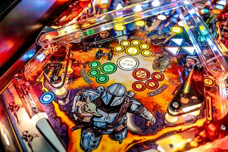 Close-up of a pinball machine with colorful lights and characters on the playfield.