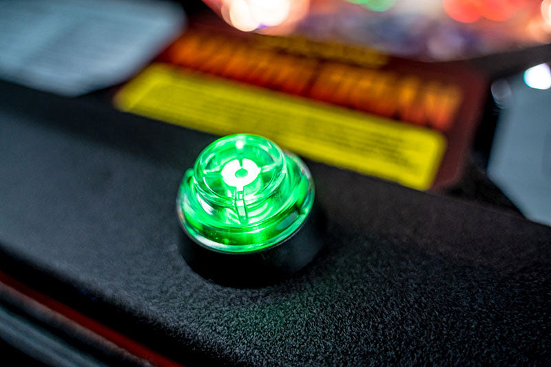 Green illuminated button on a textured surface with blurred background