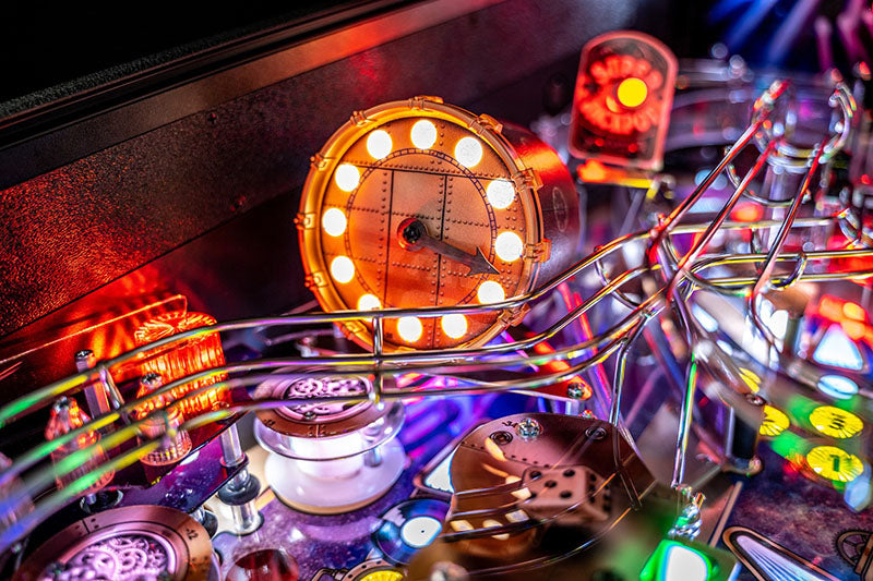 Close-up of a pinball machine with glowing lights and reflective surface.