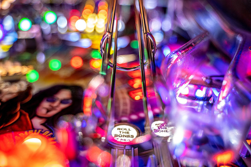 Close-up of a pinball machine with colourful lights and a blurred background