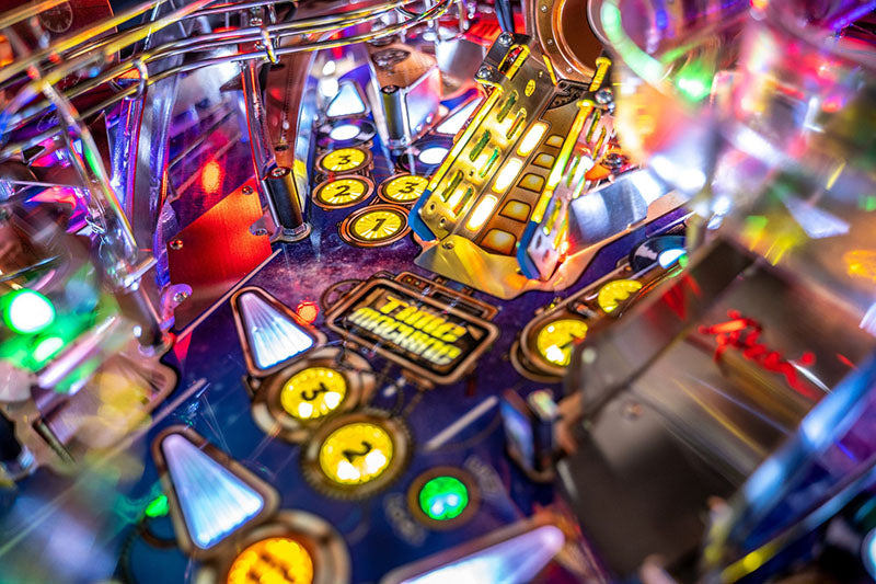 Close-up of a colourful pinball machine with various lights and buttons.
