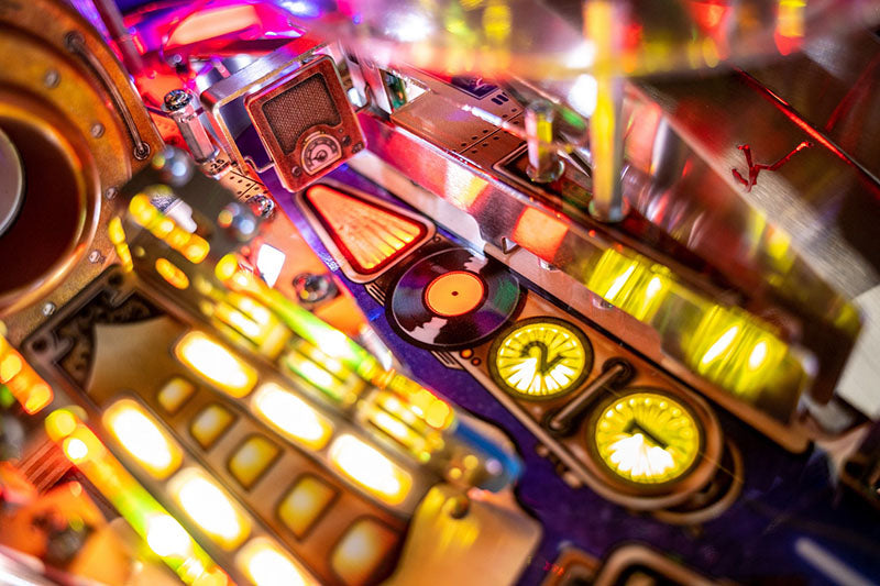 Close-up of a colourful pinball machine with glowing lights and buttons.