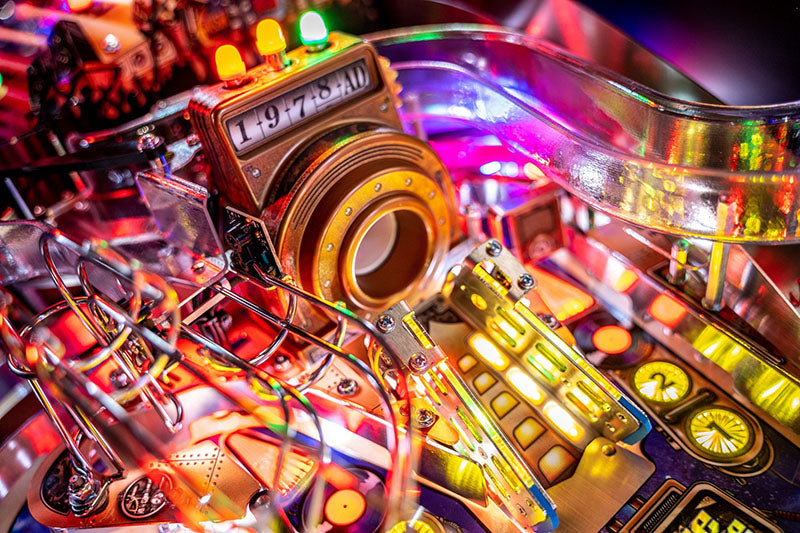 Close-up of a colourful pinball machine with lights and mechanical components.