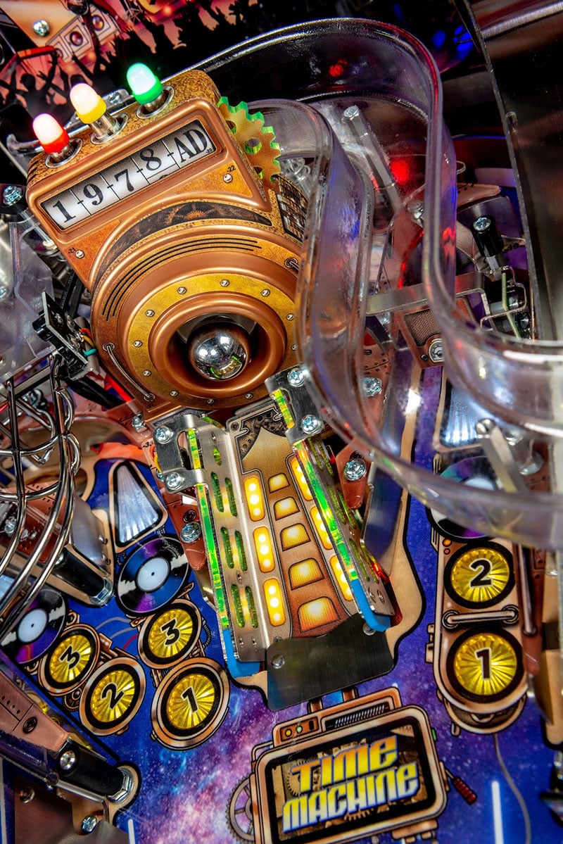Close-up of a pinball machine with colourful lights and mechanical components.
