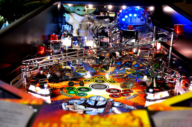 Close-up of a pinball machine with colorful playfield and lights.