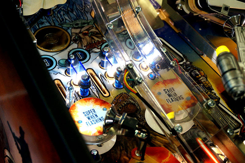 Close-up of a pinball machine with various components and lights.
