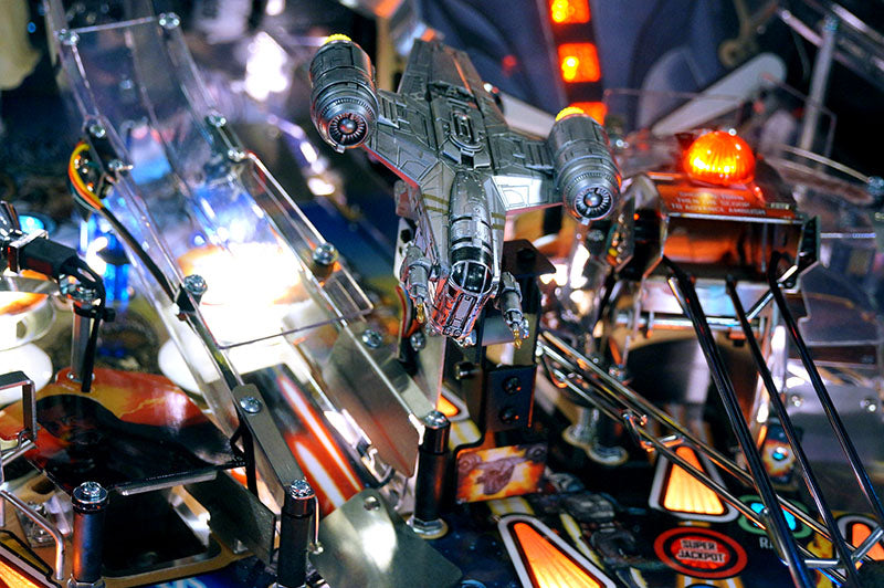Close-up of a pinball machine with a spaceship figure and colorful playfield.