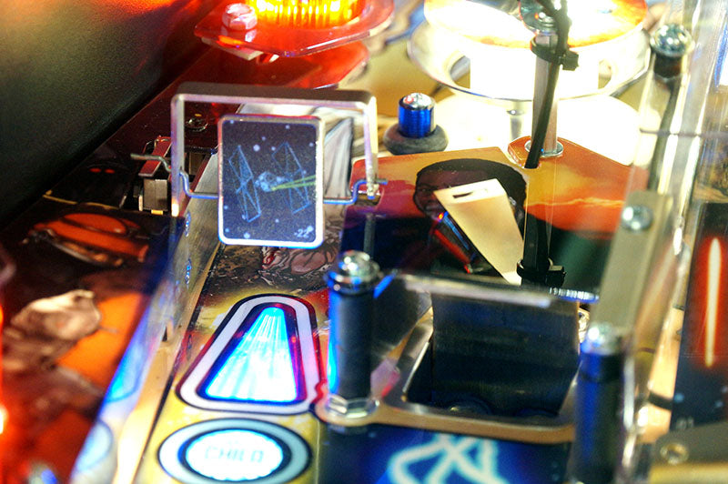 Close-up of a pinball machine with colorful lights and components.