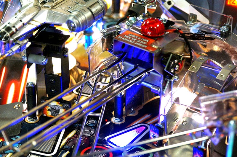 Close-up of a pinball machine with intricate details and colorful lights.