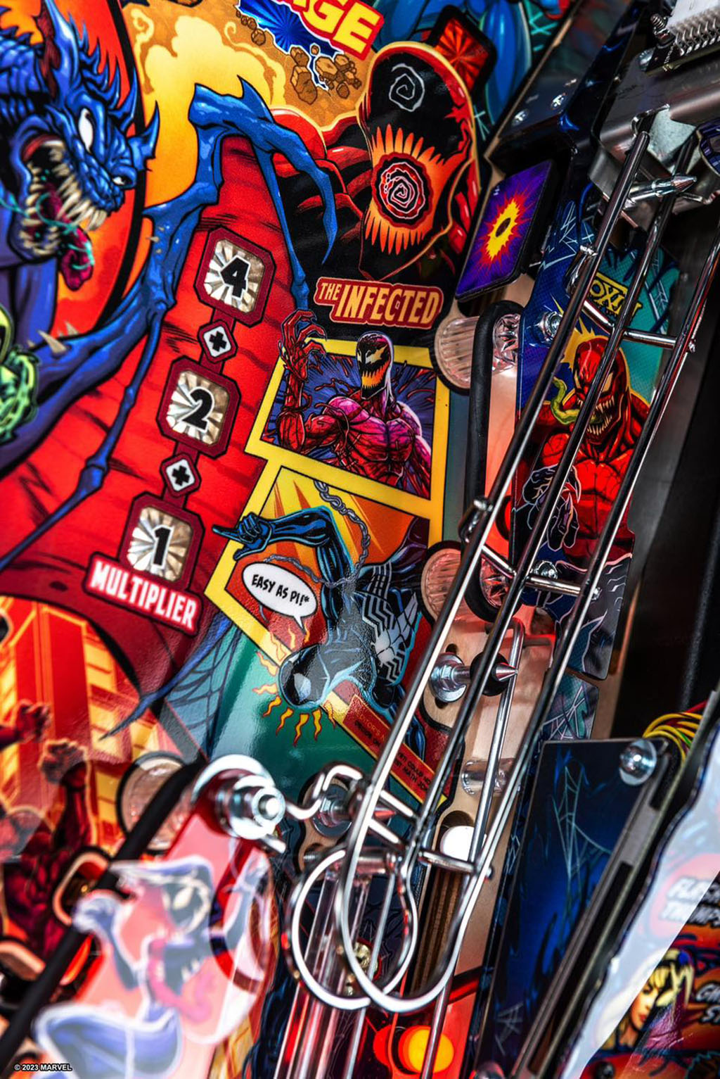 Close-up of a colourful pinball machine with various Venom themed symbols and text.