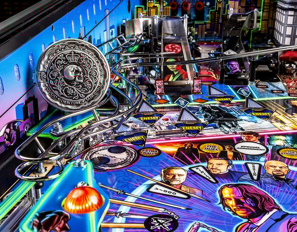 Pinball machine with a coin on top, featuring colourful John Wick artwork and game elements.