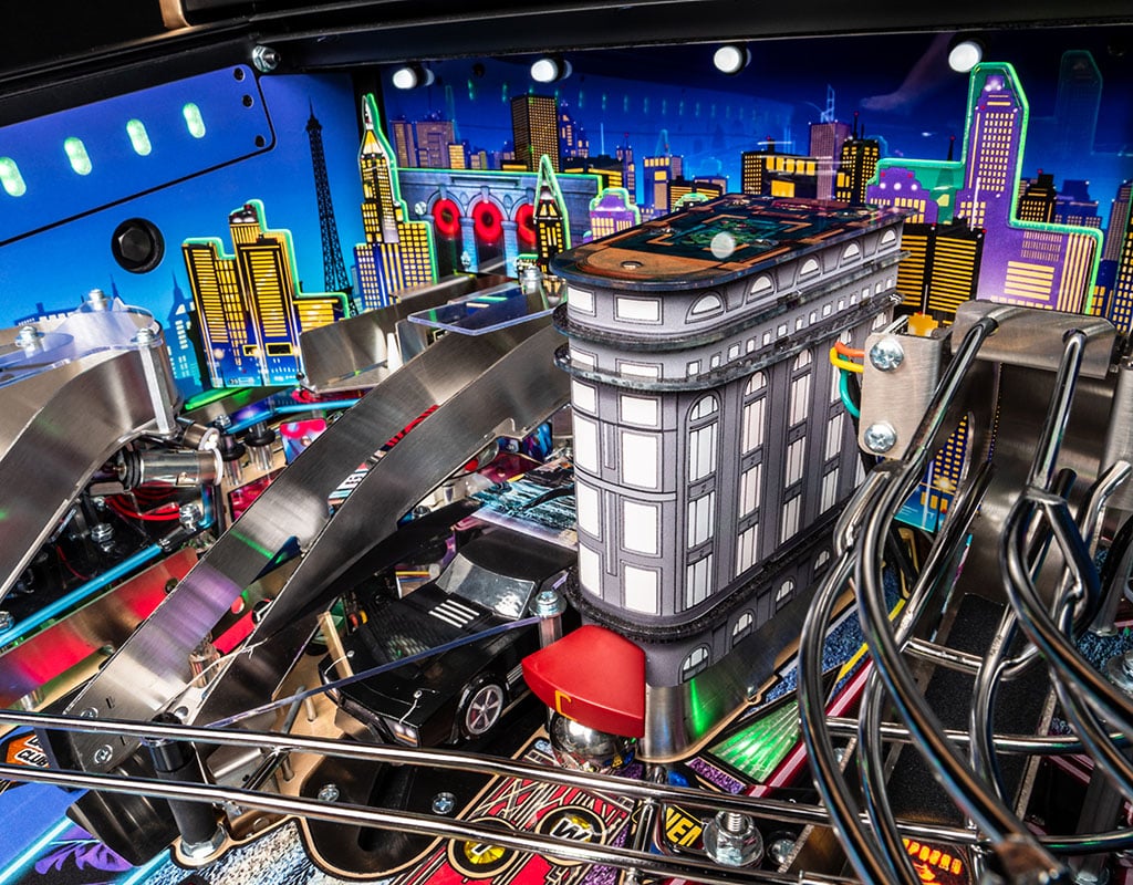 Close-up of a pinball machine with a colourful cityscape featuring the iconic continental hotel. 