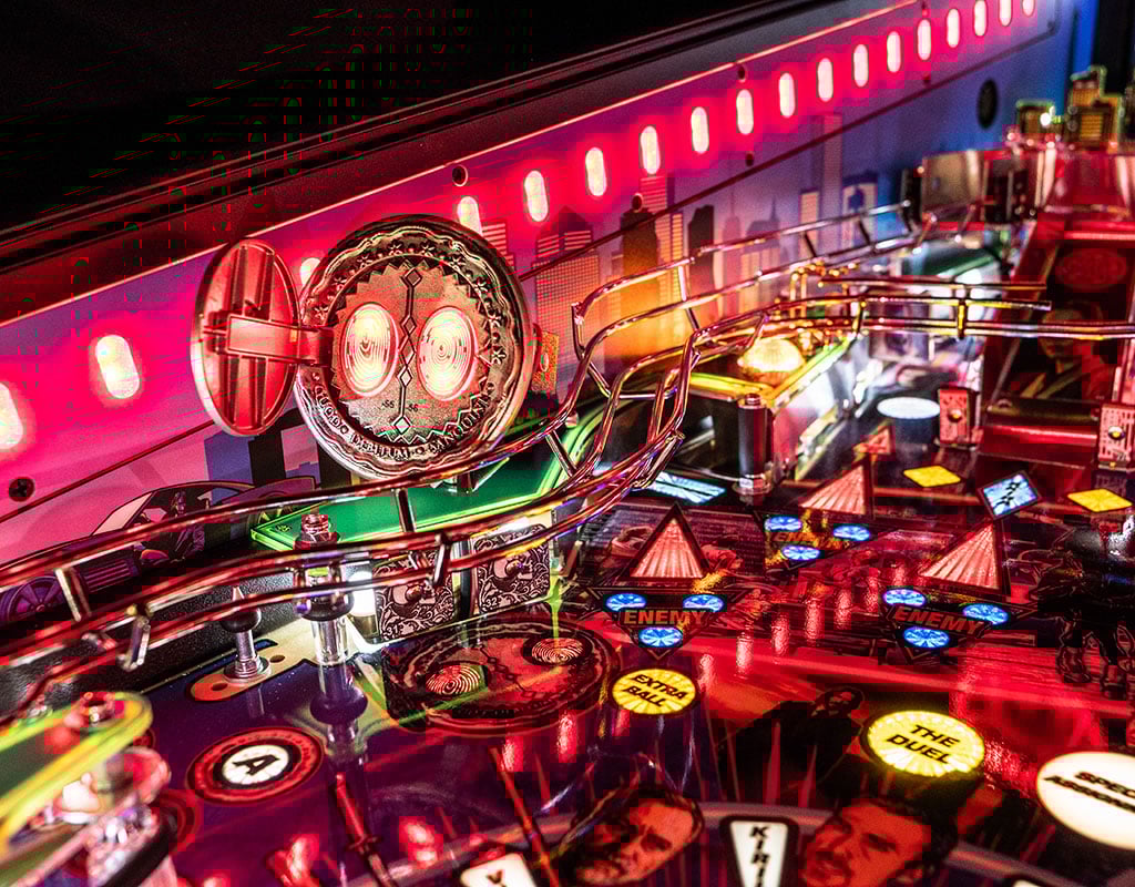 Close-up of a pinball machine with vibrant neon lights and detailed John Wick artwork.