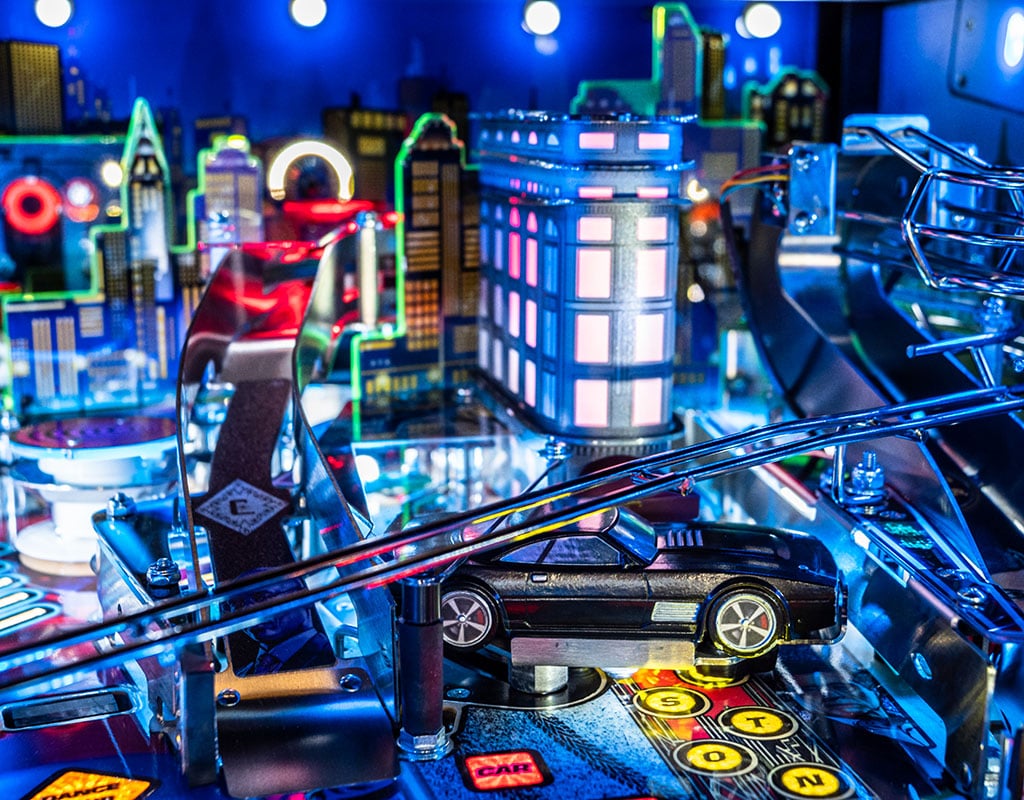 Pinball machine with neon lights and a car figure in a cityscape background