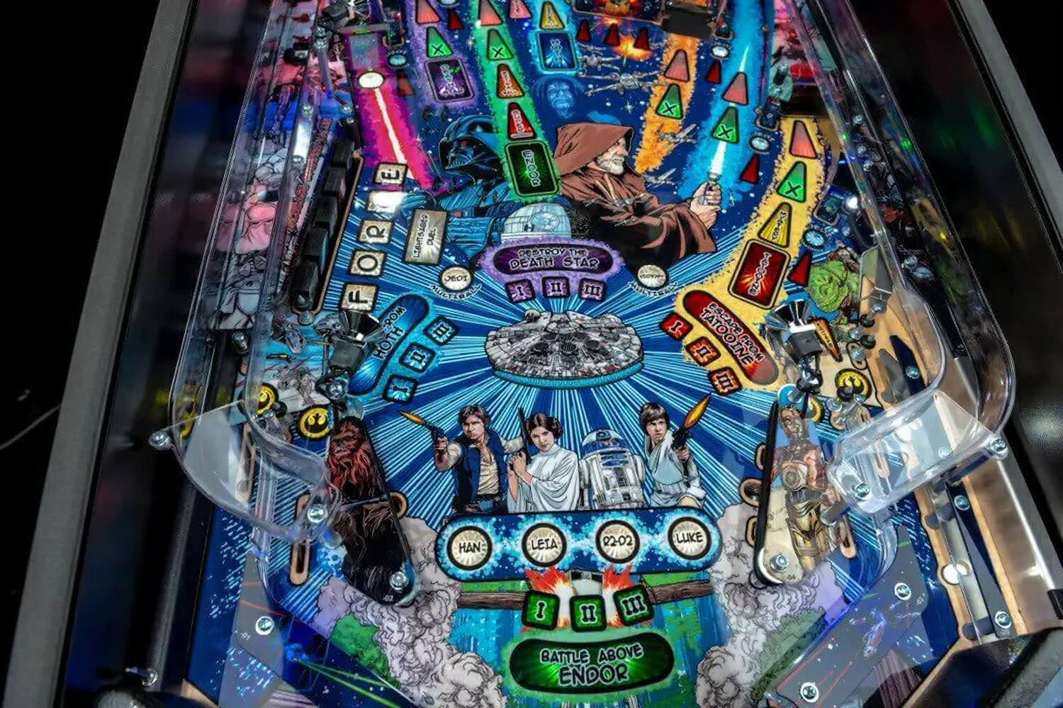 Close-up of a colorful pinball machine with various symbols and figures on the playfield.
